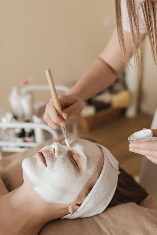 Mujer recostada a la que se le esta aplicando una masacarilla facial