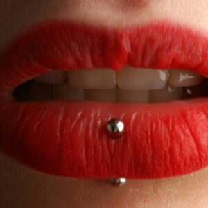 Labios pintados de rojo con un piercing el el centro del labio inferior
