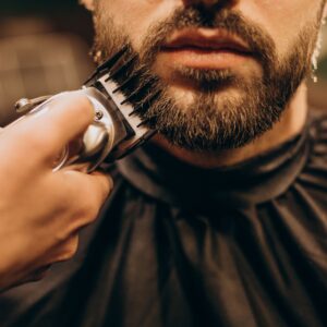 Hombre al que le estar recortando la barba con maquina