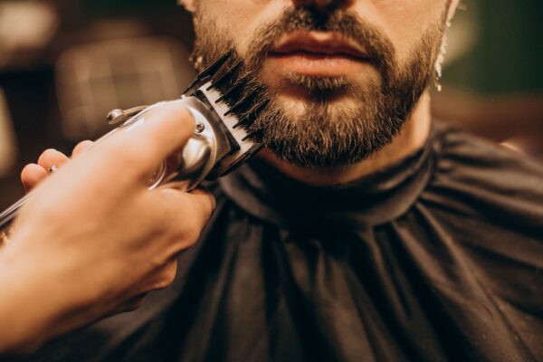 Hombre al que le estar recortando la barba con maquina