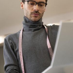 Podemos ver un personal shopper con una cinta de costura sobre el cuello y con un portátil en las manos