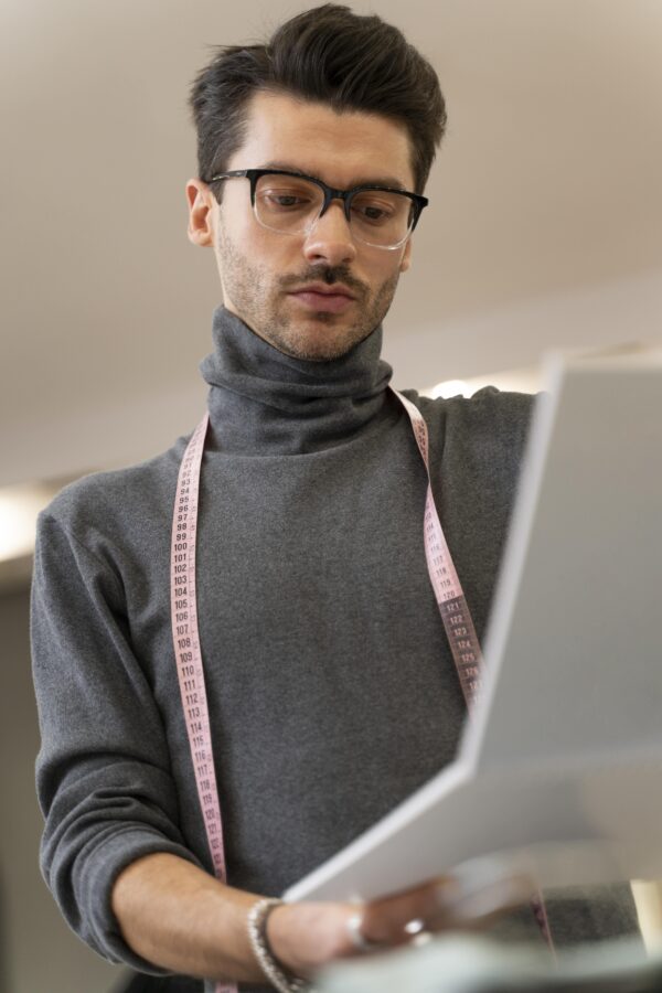 Podemos ver un personal shopper con una cinta de costura sobre el cuello y con un portátil en las manos
