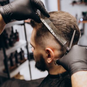 Estilismo y Peluquería Masculina-Hombre de cabello oscuro al que le están haciendo un corte de pelo