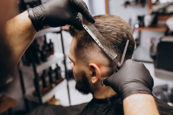 Estilismo y Peluquería Masculina-Hombre de cabello oscuro al que le están haciendo un corte de pelo